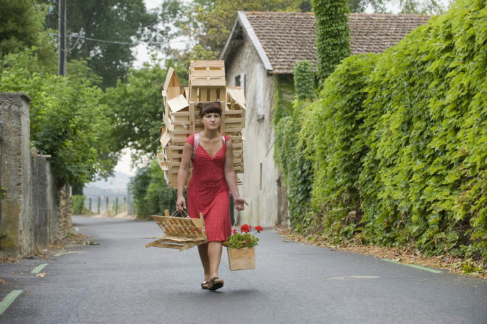 Gabriela Oberkofler, Buggelkraxen, photographie couleur de l'artiste transportant une maison en bois et cagettes sur le dos 2010