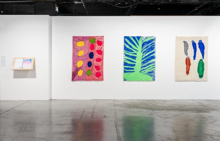 Karima, Fadma et Allal El Karmoudi Douar Yassinen, 2017 - 2026 Ensemble de trois tapis (laine de Nouvelle-Zélande, fil acrylique et toile en polyester), 90 x 140 cm chacun, sélection de dessins réalisés par Fadma et Allal Karmoudi au stylo à bille, pastel et crayons de couleurs sur papier. Courtesy de l’artiste. © La Condition Publique & Le Cube - independent art room photo: Frédéric IOVINO